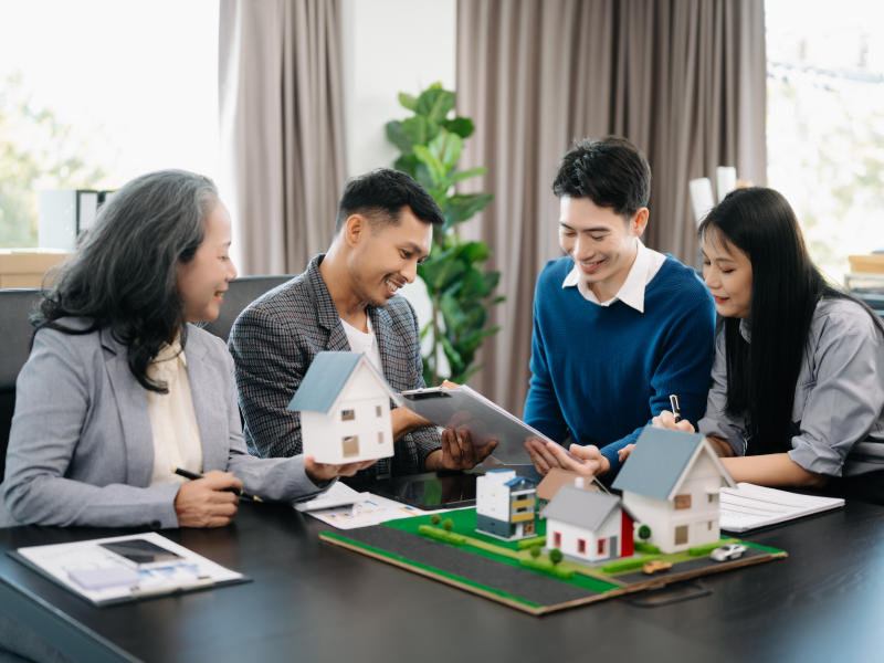 Business professionals discussing property models around a table